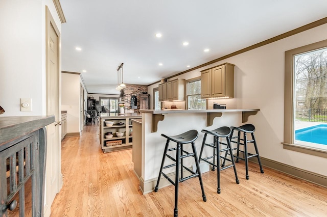 kitchen featuring crown molding, a kitchen breakfast bar, a peninsula, and light wood-style floors