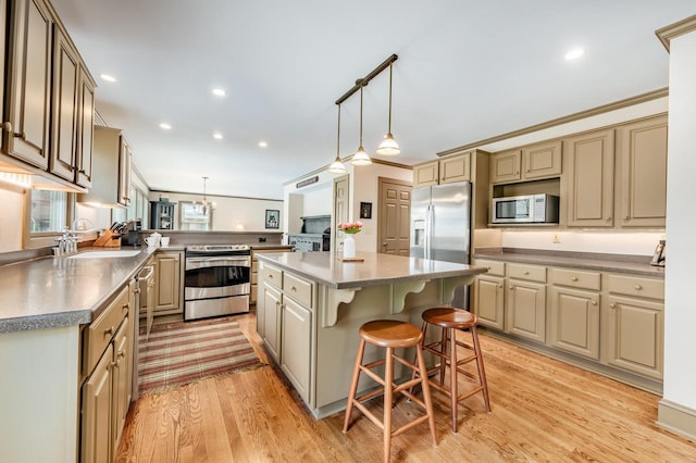 kitchen featuring a sink, light wood-type flooring, a peninsula, a kitchen island, and appliances with stainless steel finishes
