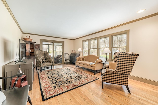 living area featuring hardwood / wood-style floors, baseboards, and crown molding