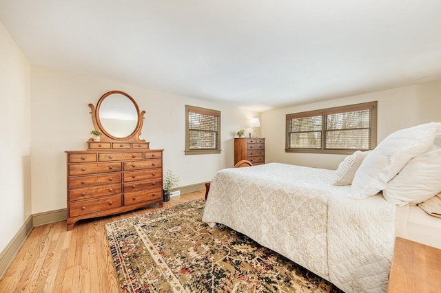 bedroom featuring baseboards, multiple windows, and light wood finished floors