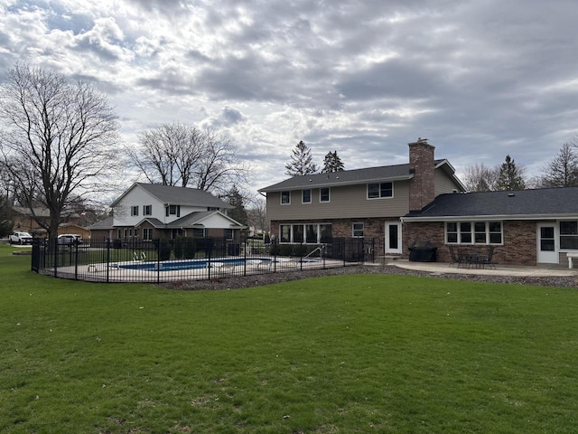 rear view of house featuring a chimney, a yard, fence, a fenced in pool, and a patio area