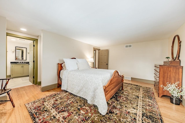bedroom featuring visible vents, light wood-style floors, and a sink