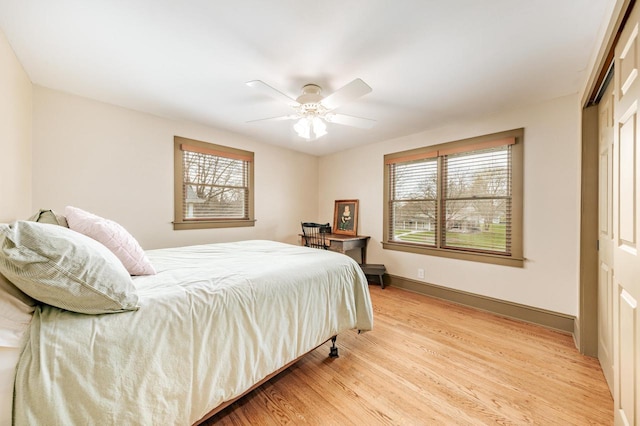 bedroom featuring baseboards, a ceiling fan, light wood-style floors, and a closet