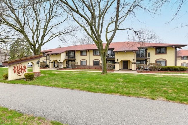 view of front of house with stucco siding, a front lawn, and a balcony