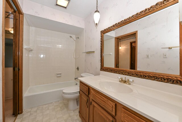 full bathroom with wallpapered walls, toilet, and vanity