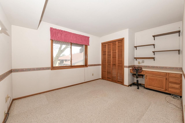 unfurnished office with light colored carpet, baseboards, and built in study area