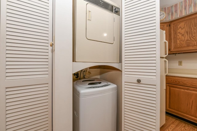 washroom featuring stacked washing maching and dryer, laundry area, and light wood-style flooring