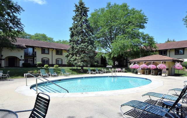 community pool with fence and a patio