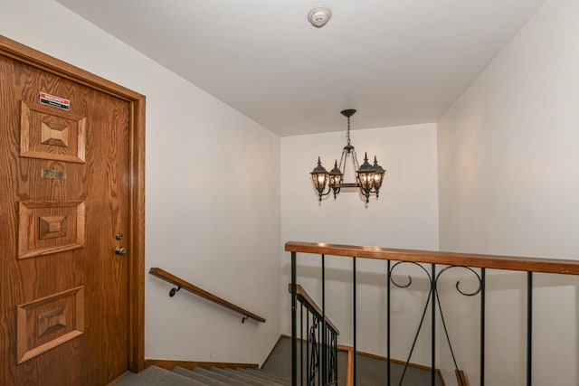 stairway featuring baseboards, carpet flooring, and a chandelier