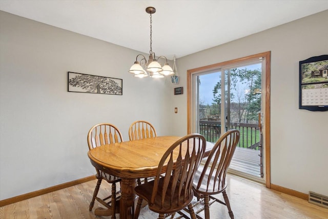 dining area with baseboards, an inviting chandelier, visible vents, and light wood-type flooring