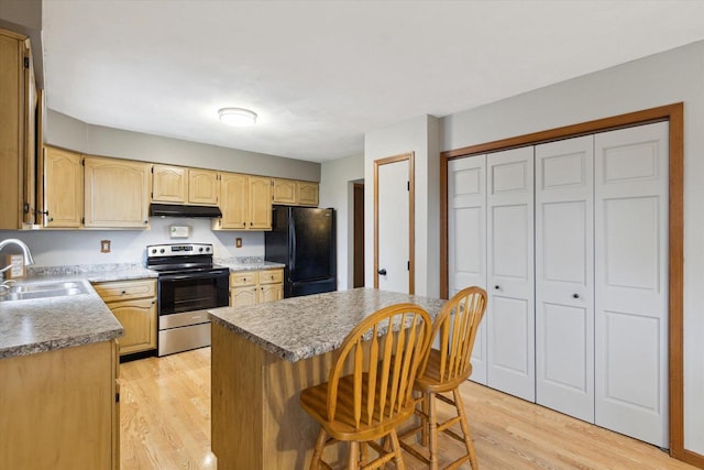 kitchen with a sink, a breakfast bar area, light wood finished floors, electric range, and freestanding refrigerator