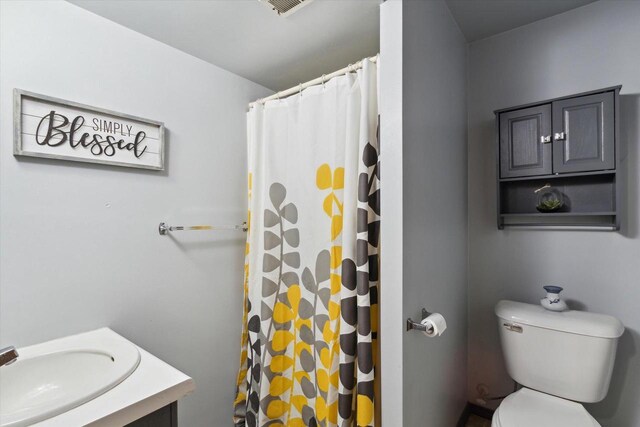 bathroom with toilet, vanity, and a shower with shower curtain