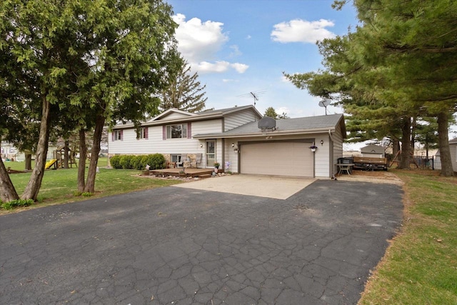 tri-level home with a garage, a front yard, and aphalt driveway