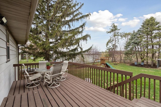 wooden terrace with a fenced backyard, outdoor dining area, a yard, and a playground