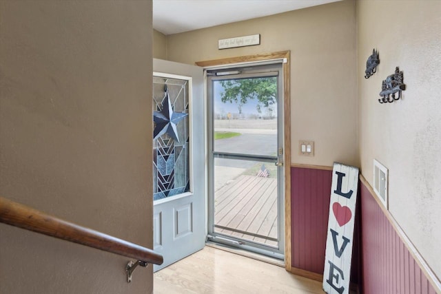 doorway featuring light wood-type flooring and wainscoting
