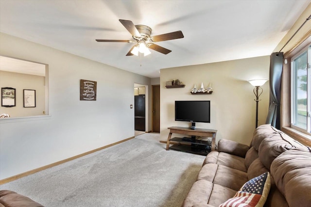 living area with ceiling fan, baseboards, and light carpet