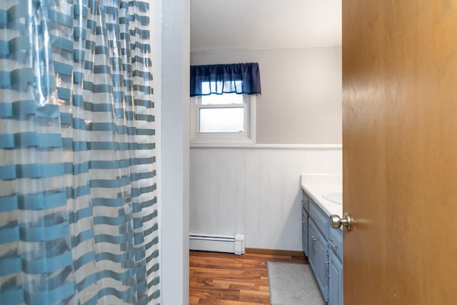 2282 Collier Ct, Green Bay, WI 54311 - bathroom with a baseboard heating unit, wood finished floors, vanity, wainscoting, and a shower with curtain
