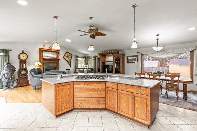 kitchen featuring stainless steel gas cooktop, a fireplace, open floor plan, and plenty of natural light