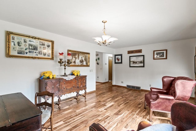 living room with a chandelier, wood finished floors, visible vents, and baseboards