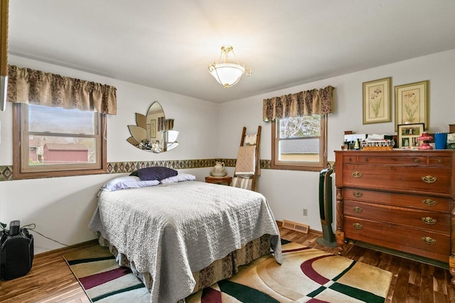 bedroom featuring baseboards, wood finished floors, and visible vents