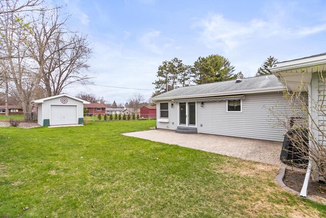back of house featuring a garage, a yard, a patio, and an outdoor structure