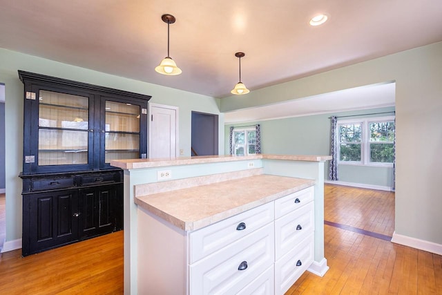 414 State Road 26, Oshkosh, WI 54904 - kitchen featuring light countertops, light wood-type flooring, decorative light fixtures, baseboards, and glass insert cabinets