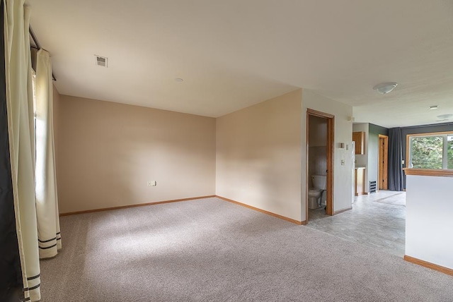 empty room featuring baseboards, light carpet, and visible vents
