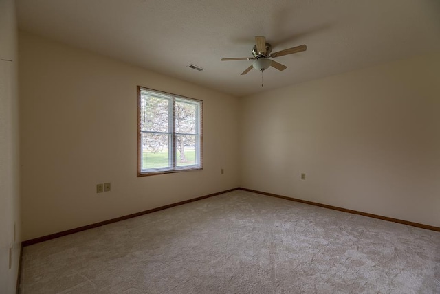 empty room featuring light colored carpet, a ceiling fan, visible vents, and baseboards