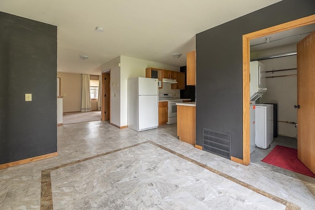 kitchen featuring visible vents, stainless steel electric range oven, brown cabinets, light countertops, and freestanding refrigerator
