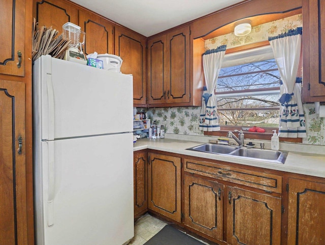 1802 S Ridge Rd, Green Bay, WI 54304 - kitchen featuring brown cabinetry, light countertops, freestanding refrigerator, and a sink