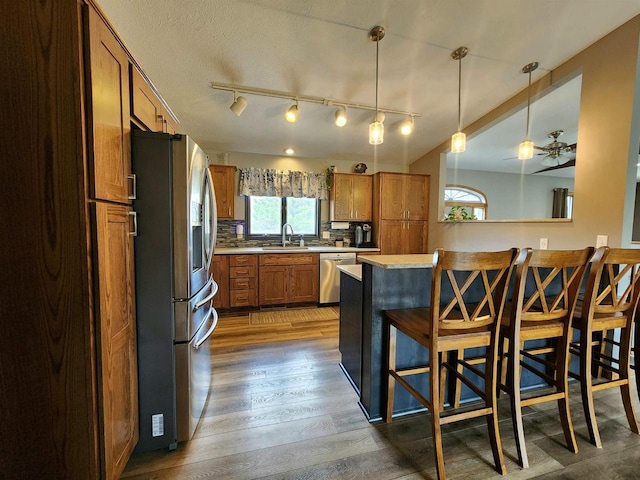 12902 Flicker Rd, Tomah, WI 54660 - kitchen featuring brown cabinets, a breakfast bar, light countertops, rail lighting, and appliances with stainless steel finishes