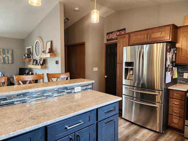 12902 Flicker Rd, Tomah, WI 54660 - kitchen featuring vaulted ceiling, brown cabinets, light wood-type flooring, stainless steel fridge with ice dispenser, and decorative light fixtures