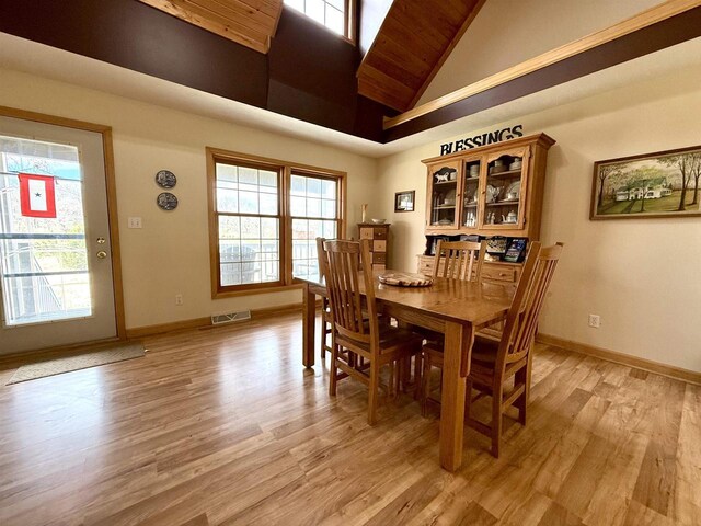 dining space with light wood-style floors, visible vents, and high vaulted ceiling