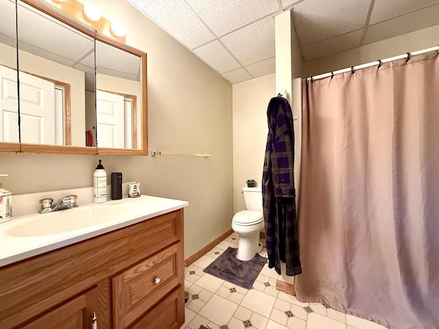 bathroom featuring toilet, vanity, curtained shower, and a drop ceiling