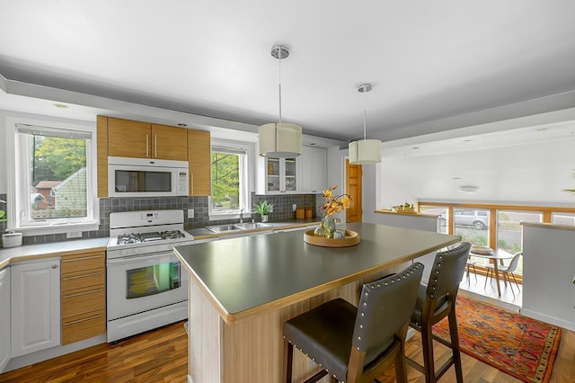 1301 Temkin Ave, Madison, WI 53705 - kitchen with white appliances, a kitchen island, backsplash, a sink, and dark wood-style flooring