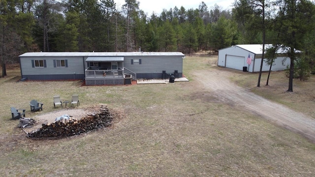 N9140 Snow Snake Trl, Necedah, WI 54646 - manufactured / mobile home featuring a detached garage, driveway, a view of trees, an outbuilding, and a wooden deck