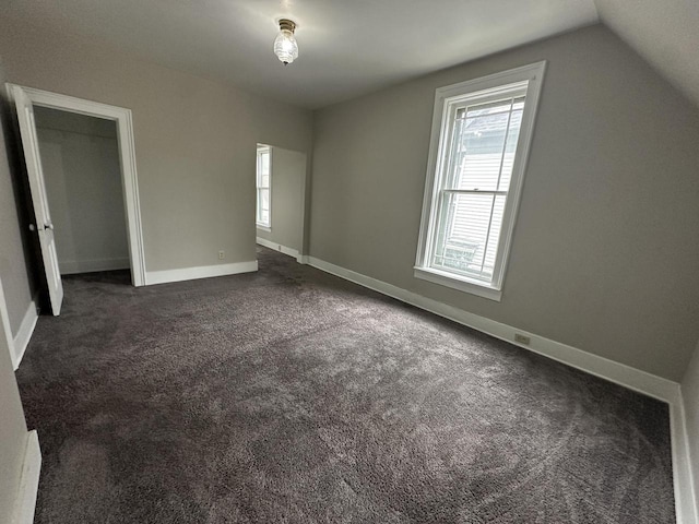 3313 W Kilbourn Ave, Milwaukee, WI 53208 - unfurnished bedroom with dark carpet, lofted ceiling, multiple windows, and baseboards