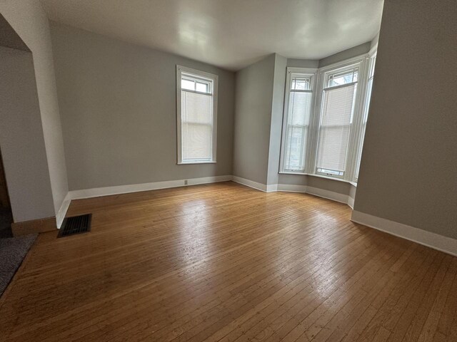 3313 W Kilbourn Ave, Milwaukee, WI 53208 - spare room featuring wood-type flooring, baseboards, and visible vents