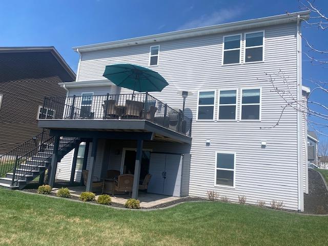 back of house with a lawn, a wooden deck, a patio, and stairs