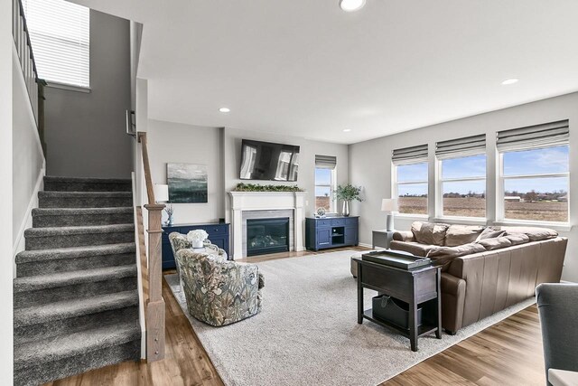 living room featuring stairway, wood finished floors, a fireplace with flush hearth, baseboards, and recessed lighting