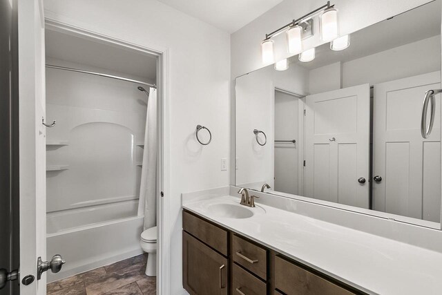 full bathroom featuring stone finish flooring, toilet, vanity, and shower / bathtub combination with curtain
