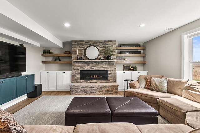 living room featuring recessed lighting, wood finished floors, visible vents, and a fireplace