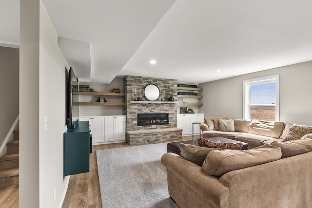 living room with stairs, a fireplace, light wood-style floors, and recessed lighting