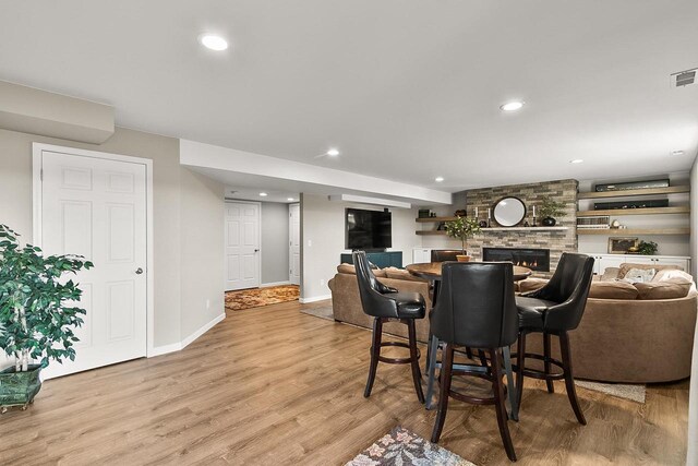 dining space featuring light wood finished floors, baseboards, recessed lighting, visible vents, and a stone fireplace