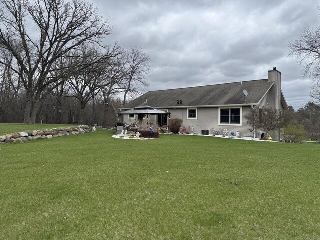 W360S10139 Markham Rd, Eagle, WI 53119 - rear view of house featuring a chimney, roof with shingles, a patio, a lawn, and a gazebo
