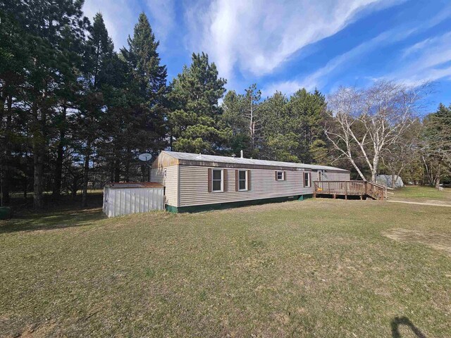 manufactured / mobile home featuring a wooden deck and a front lawn