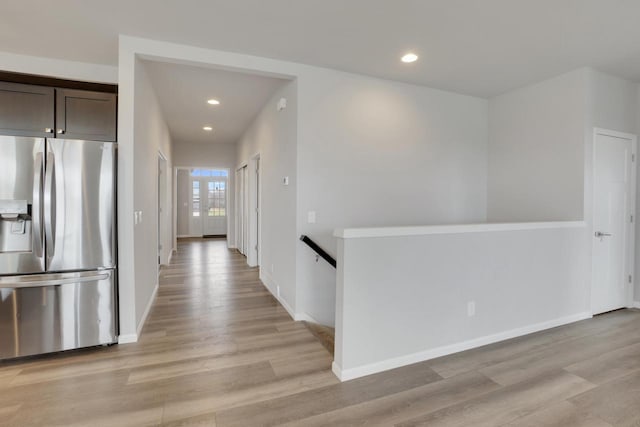 hallway with light wood finished floors, baseboards, recessed lighting, and an upstairs landing