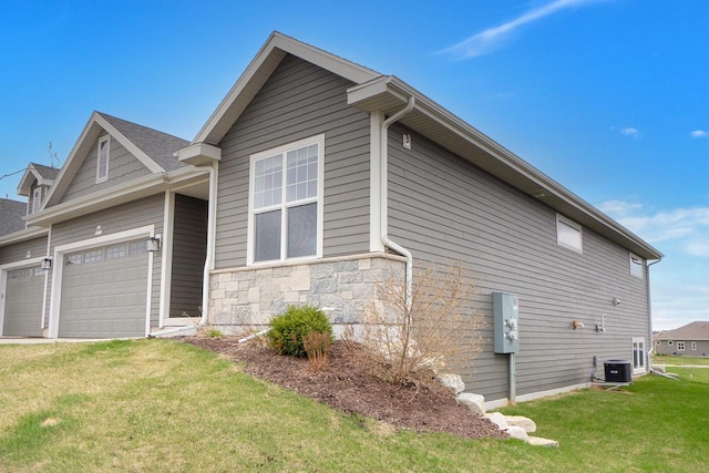 view of side of property with central AC unit, stone siding, a yard, and a garage