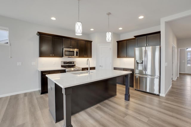 kitchen with dark brown cabinets, a sink, stainless steel appliances, light wood finished floors, and light countertops