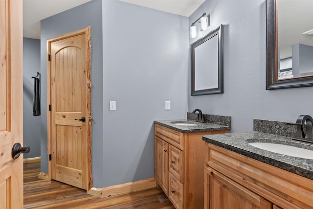 905 Plymouth Ct, Nekoosa, WI 54457 - bathroom featuring two vanities, wood finished floors, and a sink